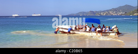 Water Taxi in partenza Grand Anse Bay beach ritorno gruppo di persone i turisti per le navi da crociera su orizzonte che sono ancorate al largo di Grenada Caraibi Foto Stock