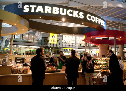 Persone che sono servite a Starbucks Coffee bar, nel terminal 5 di Heathrow, London REGNO UNITO Foto Stock