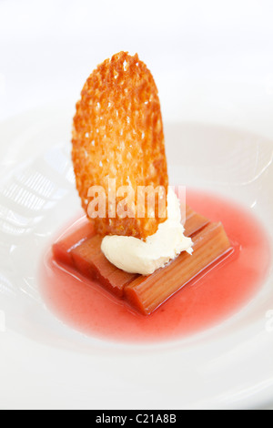 Dessert di rabarbaro speziato con panna e un brandy snap biscotto. Foto Stock