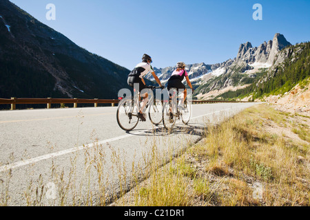 Una giovane coppia corrono in bici fino a mountain pass. Cascate del nord dello stato di Washington, Highway 20, STATI UNITI D'AMERICA. Foto Stock