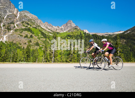 Un giovane uomo e donna cavalcare le loro biciclette su strada statale 20 nel North Cascades dello Stato di Washington. Foto Stock