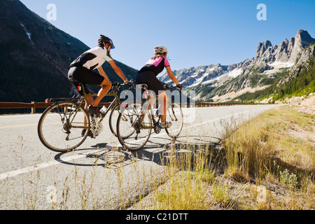 Una giovane coppia corrono in bici fino a mountain pass. Cascate del nord dello stato di Washington, Highway 20, STATI UNITI D'AMERICA. Foto Stock