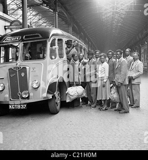 1950, Londra e gli immigrati d'oltremare appena arrivati dai Caraibi alla stazione ferroviaria di Victoria aspettano di salire a bordo del loro trasporto, un Guy Vixen pullman. Foto Stock