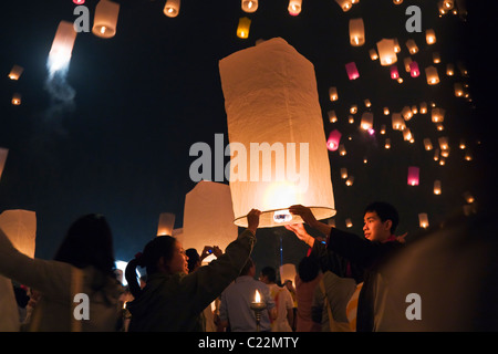 Lancio di festeggianti khom loi (sky lanterns) nel cielo notturno durante il Yi Peng festival. San Sai, Chiang Mai, Thailandia. Foto Stock