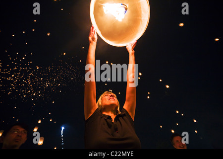 Una donna rilascia un khom loi (sky) lanterna nel cielo notturno durante il Yi Peng festival. San Sai, Chiang Mai, Thailandia. Foto Stock