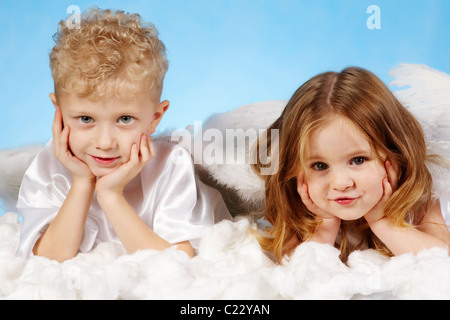 Piccolo Ragazzo e ragazza in costume angelico giacente sulla nuvola bianca Foto Stock
