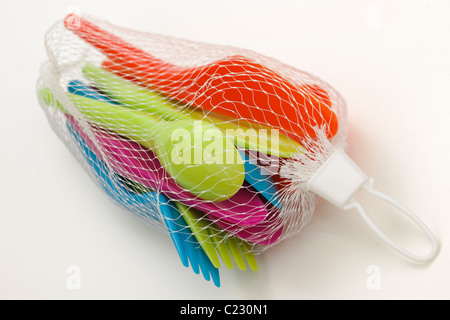 Impostare delle colorate in plastica coltelli picnic forchette e cucchiai in un bianco borsa a rete Foto Stock