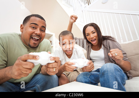 Famiglia americana africana, genitori e figlio, divertendosi console video games insieme Foto Stock