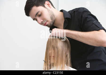 L'uomo il taglio di una giovane donna capelli in parrucchieri Foto Stock