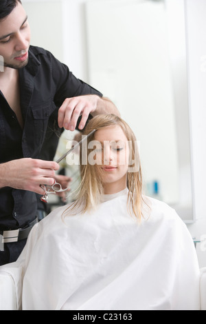 L'uomo il taglio di una giovane donna capelli in parrucchieri Foto Stock