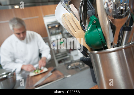 Mid- adulto chef lavora con utensile titolare in primo piano Foto Stock