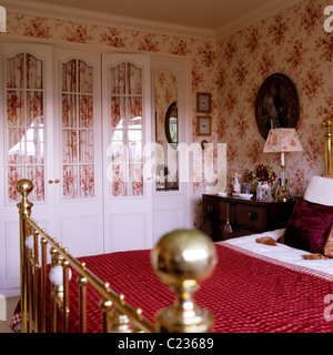 Panno rosso su ottone incorniciato letto in camera da letto con toile de jouy wallpaper Foto Stock