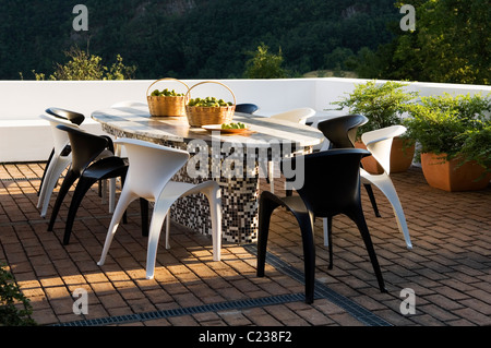 Designer italiano sedie da pranzo intorno al tavolo piastrellato sul mattone pavimentato terrazza Foto Stock