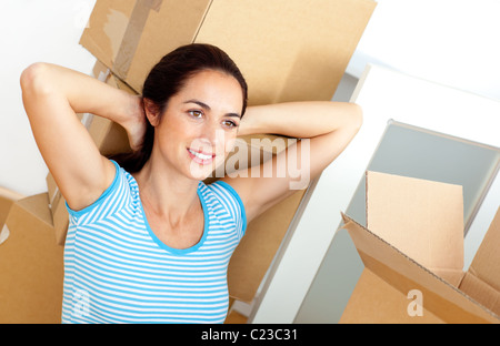 Rilassata giovane donna seduta sul pavimento dopo aver disimballato cartoni Foto Stock