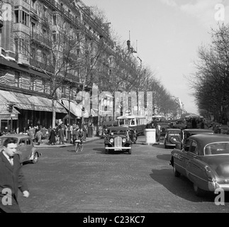 Parigi, Francia, 1950s. Un quadro storico di un affollato viale acciottolato con automobili d'epoca e persone. Foto Stock