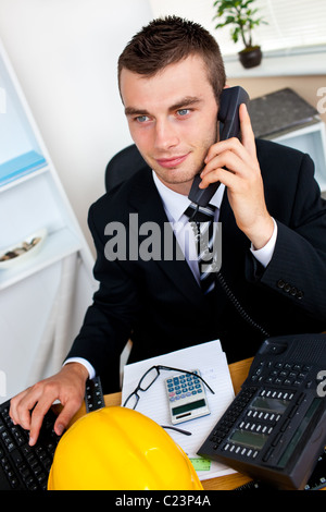 Giovani caucasici imprenditore parlando al telefono seduto alla sua scrivania Foto Stock