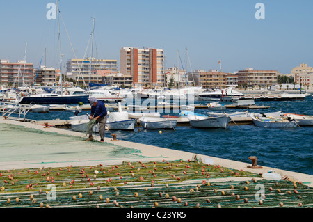 Un pescatore di tende per le sue reti sulla banchina del porto nel Mediterraneo Porto di San Pedro del Pinatar, Murcia, Spagna. Foto Stock