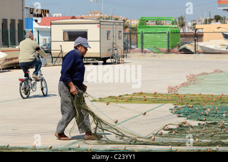 Un pescatore di tende per le sue reti sulla banchina del porto nel Mediterraneo Porto di San Pedro del Pinatar, Murcia, Spagna. Foto Stock