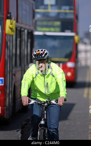 Un ciclista in sella a all'interno del movimento di red London double decker bus Foto Stock