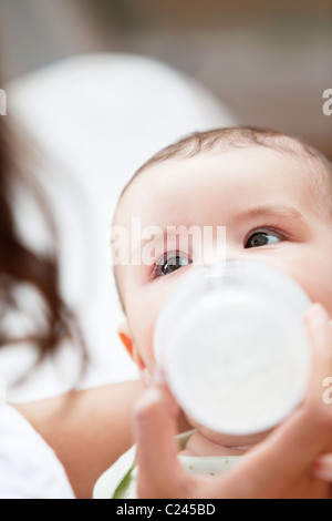 Close-up di un baby boy bottiglia-alimentato da sua madre a casa Foto Stock