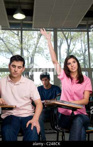 Femmina studente universitario alzando la mano in classe Foto Stock