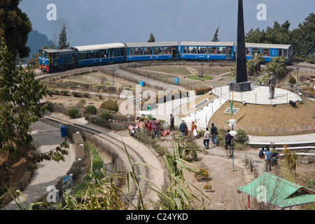 Il trenino passa attraverso Batasia Loop e il memoriale di guerra a Darjeeling, West Bengal, India. Foto Stock