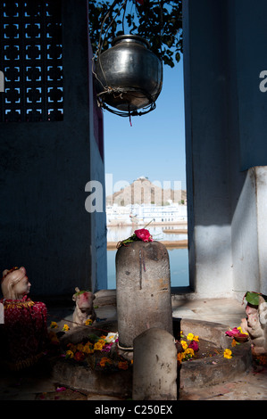 Un piccolo santuario in Pushkar' lakeshore con il Varaha tempio sulla cima della collina in background. Foto Stock