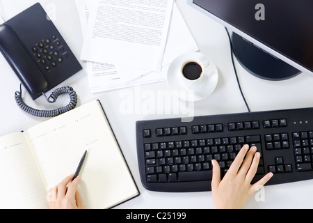 Immagine di un luogo di lavoro con ufficio oggetti e mani femminili Foto Stock