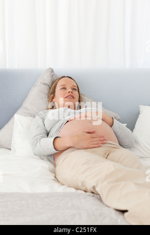 Bella donna incinta in appoggio su un letto Foto Stock