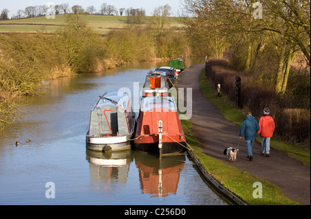 La gente camminare cane lungo il percorso a fianco di una chiatta su Foxton blocca vista dal Ponte di Arcobaleno lungo il Grand Union Canal a Foxton Foto Stock