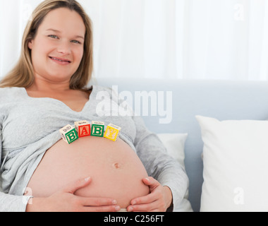 Giovane donna incinta con bambino lettere sul suo ventre Foto Stock