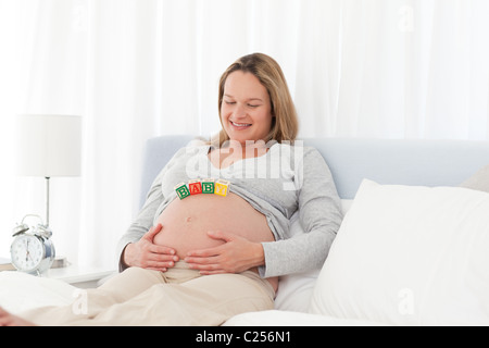 Felice donna incinta con bambino lettere sul suo ventre Foto Stock