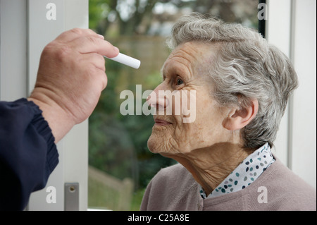 Medico controllo dell'occhio per la dilatazione della pupilla dopo un incidente / caduta di una donna anziana Foto Stock