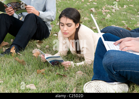 Signora donna, ragazza, sedersi, situati, giù, Vista, leggere, lettura, utilizzando, notebook Mac, sedersi giù, laici, posa, a, università, campus. Foto Stock