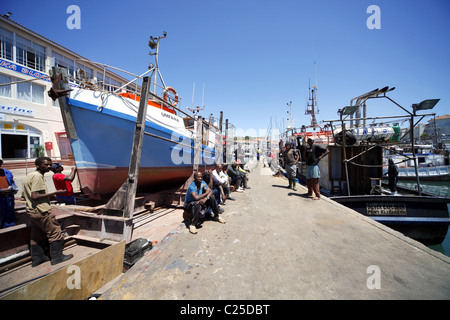 Colorati di nero lavoratori sedersi vicino a barca da pesca di ST. Francesco Harbour Eastern Cape SUD AFRICA 26 Gennaio 2011 Foto Stock