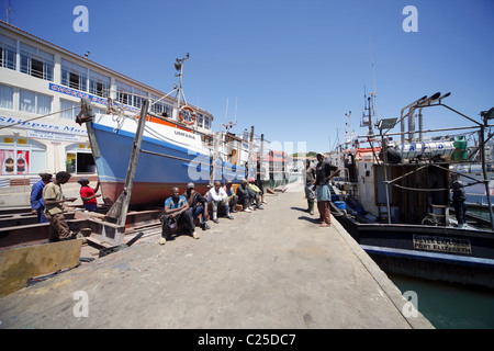 Colorati di nero lavoratori sedersi vicino a barca da pesca di ST. Francesco Harbour Eastern Cape SUD AFRICA 26 Gennaio 2011 Foto Stock