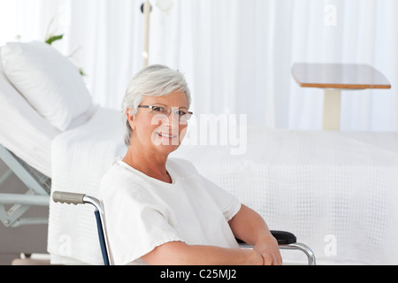 Senior donna nella sua sedia a rotelle guardando la telecamera Foto Stock