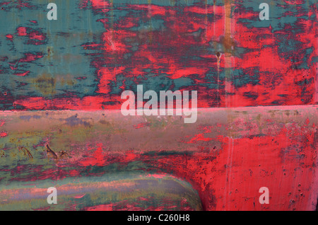 Abstract di blu e di rosso sfald vernice sul lato di un vecchio abbandonato arrugginimento carrello Foto Stock