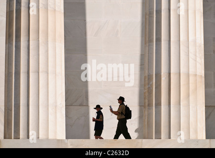 WASHINGTON DC, Stati Uniti - Un maestro di scout e uno scout si trova accanto alle imponenti colonne doriche del Lincoln Memorial, sottolineando la scala monumentale della struttura neoclassica. Le colonne alte 44 piedi, ognuna realizzata in marmo Colorado Yule, si innalzano sopra i visitatori. La scena illustra l'imponente presenza architettonica del monumento. Foto Stock