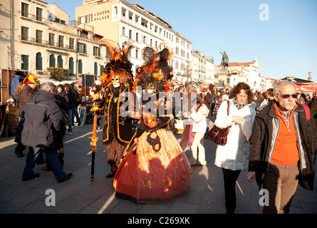 Caratteri mascherati miscelazione con la folla sul lungomare al carnevale di Venezia, Venezia, Italia Foto Stock