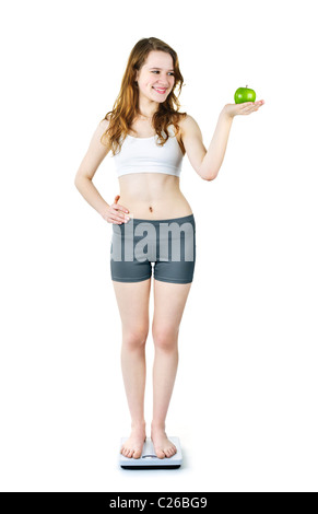 Felice sano giovane donna azienda mela verde permanente sulla bilancia da bagno Foto Stock