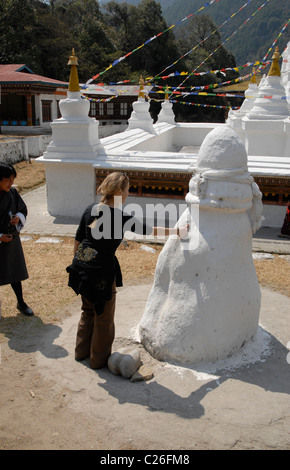 Un turista toccando un foro in una famosa pietra, Chorten Kora, Trashiyangtse, Est Bhutan Foto Stock