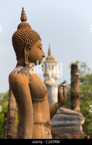 A piedi il Buddha e il Buddha seduto al Wat Sa Si, parte di Sukothai Parco Storico in Thailandia Foto Stock