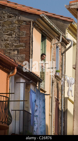 Uomo che guarda fuori da una finestra nel sud della cittadina francese di Collioure Foto Stock