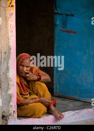 Vecchia signora seduta nel vano della porta in Orchha (India) a guardare il mondo che passa da Foto Stock