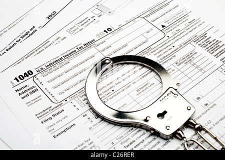 In manette su un americano 1040 imposta sul reddito modulo indicante la frode fiscale e l'evasione Foto Stock