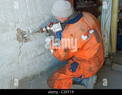 Fori di perforazione in una casa di mattoni. l uomo con un trapano. Foto Stock