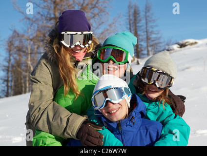 Ritratto di quattro giovani in maschere da sci abbracciando Foto Stock