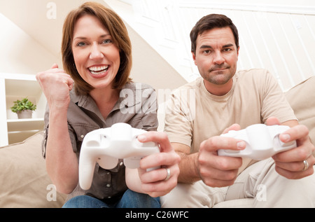 Uomo e donna coppia sposata si diverte a giocare computer gioco per console insieme, la donna sta celebrando battendo l'uomo Foto Stock