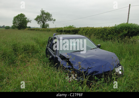 Una si è schiantato auto blu giace abbandonata in un campo al di fuori del modo Foss vicino a Warwick in Inghilterra. Foto Stock
